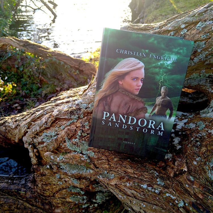 Bogen Pandora Sandstorm på en væltet træstamme tæt ved vand